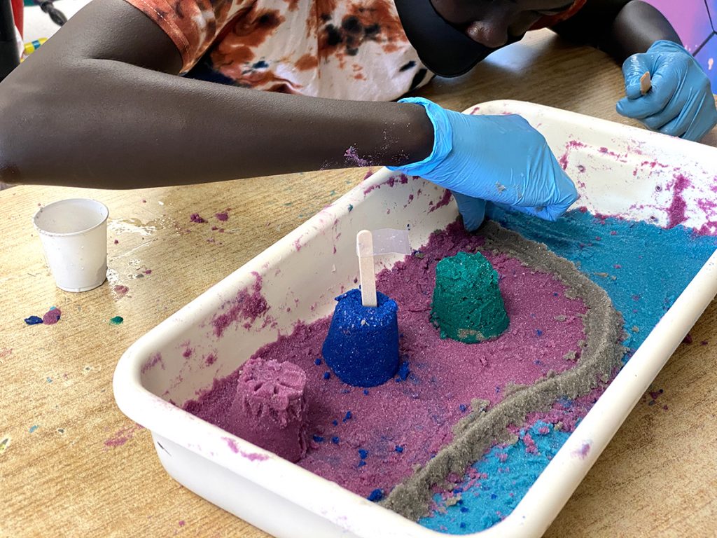 student creating sand art in plastic bin